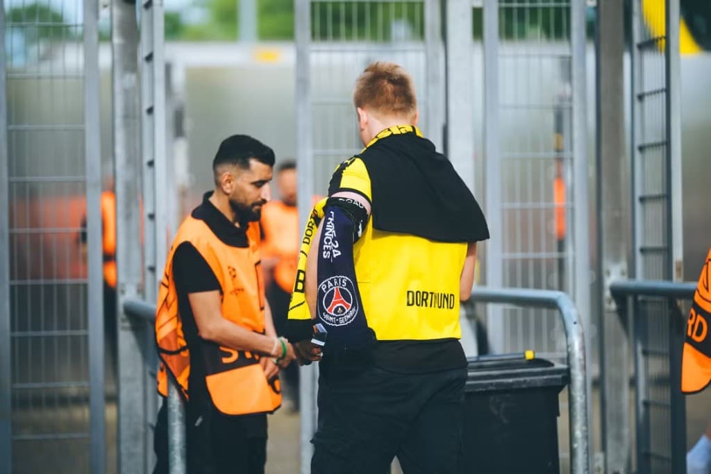Event staff in high-visibility vests checking tickets at a stadium entrance